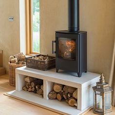 a wood stove sitting on top of a white shelf next to a basket filled with logs