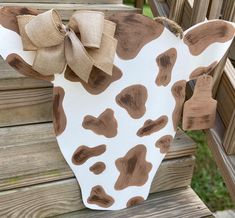 a cow head with a large bow on it's back sitting on a wooden bench