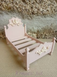 a pink doll bed sitting on top of a carpeted floor next to a stone wall