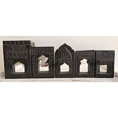 four decorative pieces are sitting on a shelf in front of a white wall and window