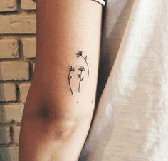 a woman's arm with a small flower tattoo on the left side of her arm