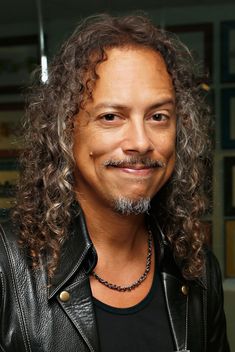 a man with long curly hair wearing a leather jacket