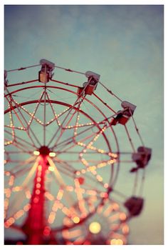 a ferris wheel is lit up at night time with the sky in the back ground