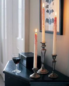 three candles on a table with a glass of wine