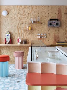 a room with various colored stools and shelves on the wall, including a piano