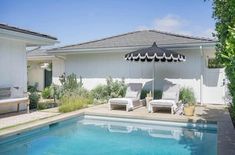 an outdoor pool area with lounge chairs and an umbrella over the swimming pool in front of it