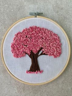 a hand embroidered tree with pink flowers on it