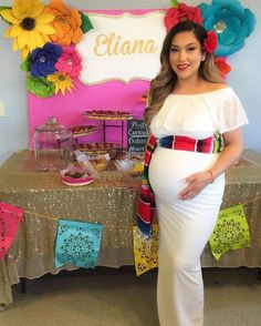 a pregnant woman standing in front of a table with flowers on it and a sign that says etna