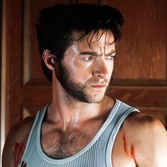 a man with blood all over his face and chest standing in front of a door