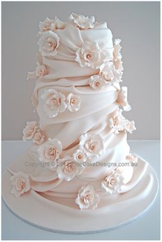 a white wedding cake with flowers on it's tiers and the top layer is covered in icing