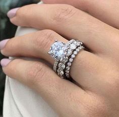 a woman's hand with two rings on her fingers and one ring in the middle