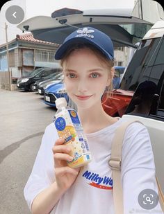 a young woman holding a bottle of milk in front of her face while standing next to a car