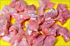 raw meat sitting on top of a yellow plate with seasoning sprinkles