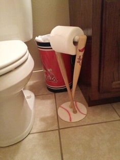 a bathroom with a toilet, trash can and baseball bat on the floor next to it