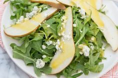 a salad with pears and feta cheese is on a white plate, ready to be eaten