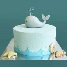 a blue cake with a white whale on top and seashells around the edges