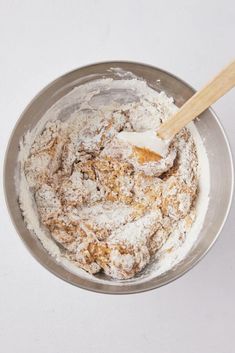 a metal bowl filled with powdered sugar and a wooden spoon