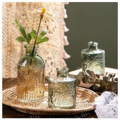 two glass vases sitting on top of a wooden table next to a doily