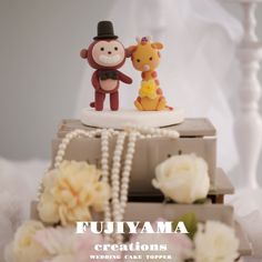 a small toy monkey and giraffe sitting on top of some books with flowers