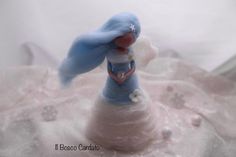 a small blue bird figurine sitting on top of a white cloth covered table