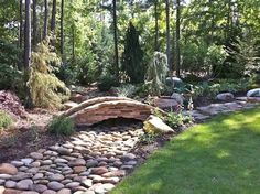 a stone bridge in the middle of a garden