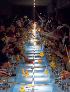 a group of people sitting at a long table with yellow rubber ducks on the table