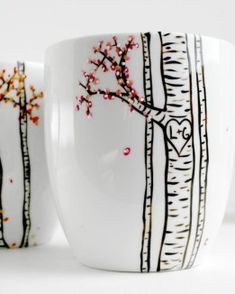 two coffee mugs with trees painted on them