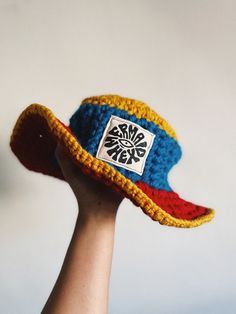 a hand is holding a crocheted hat with a patch on it