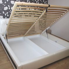 an open bed frame sitting on top of a hard wood floor next to a wall