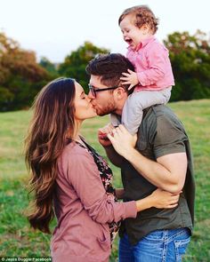 a man and woman kissing while holding a small child