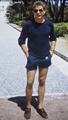 a man standing on the sidewalk in shorts