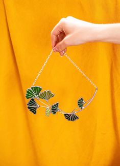 a woman holding onto a chain with green leaves on it and hanging from it's end