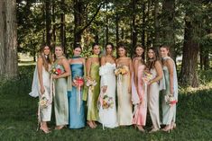 a group of women standing next to each other wearing dresses and holding bouquets in their hands