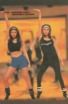 two young women are dancing in the middle of a dance studio with their arms up