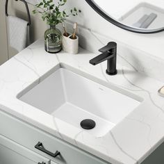 a bathroom sink with a black faucet and white marble counter top next to a mirror