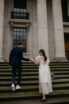 a man and woman standing on steps holding hands