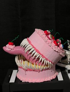 there is a cake that looks like a monster's mouth with cherries on it