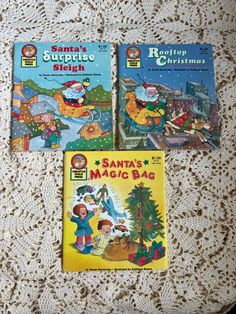 three children's books sitting on top of a white lace tablecloth covered table