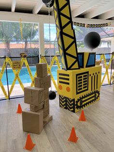 a large crane sitting in the middle of a room filled with boxes and orange cones