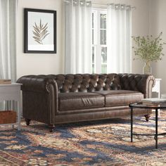 a living room with a couch, coffee table and rugs on the floor in front of windows