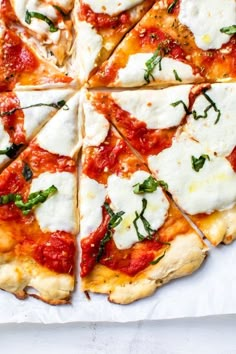 a pizza that is cut into eight pieces and sitting on a table with sauce, mozzarella and parmesan cheese