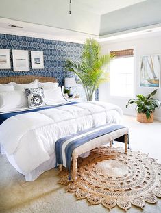 a bedroom with blue and white wallpaper has a large bed in the corner, along with a rug on the floor