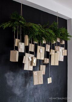 a bunch of bags hanging on a wall with christmas tree branches in the middle and tags attached to them