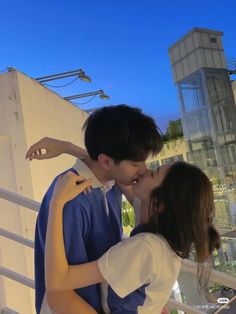 a man and woman kissing each other on the balcony