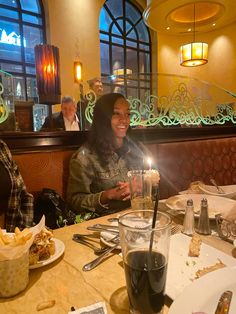 two women sitting at a table with food and drinks in front of them, smiling for the camera