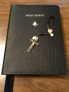 a book with a cross and rosary on it sitting on top of a wooden table