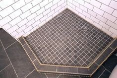 a tiled shower stall with black and white tiles