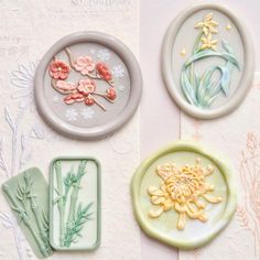 three plates with designs on them sitting next to some flowers and bamboo sticks in the middle