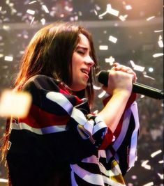 a woman singing into a microphone with confetti in the background