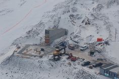 an aerial view of a construction site in the middle of snow covered mountains and hills